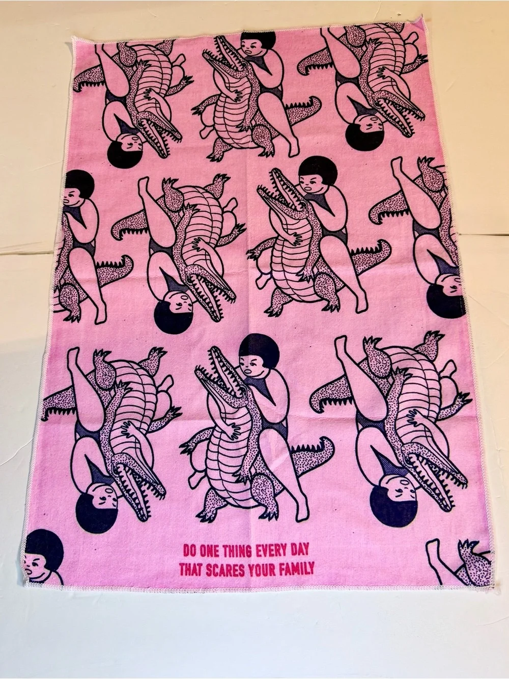 Funny pink dish / tea towel with a repeating print of a person wrestling an alli